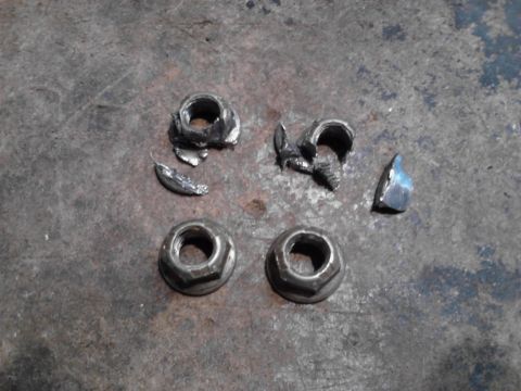 1995 Ford Bronco - Several nuts and bolts appear to be damaged or broken, lying on a rough surface.