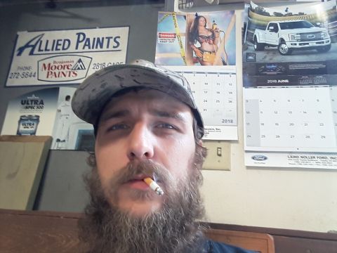 1994 Ford Bronco - A man is seen smoking a cigarette in front of various calendars and advertisements on a wall.