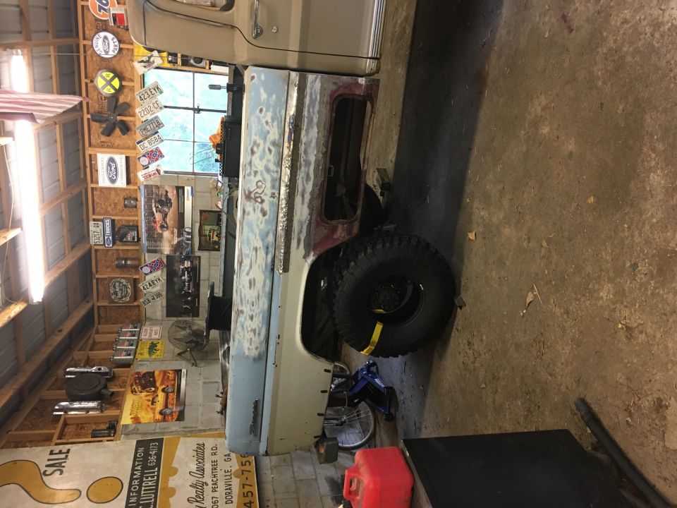 1967 Ford F-250 truck body in primer, side view, undergoing restoration in a garage