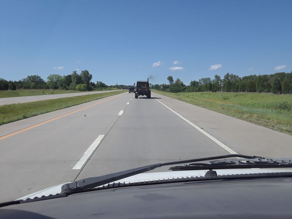 Two trucks driving on a highway under a clear blue sky