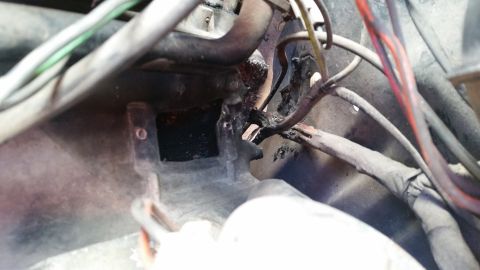 1985 Ford Bronco - A close-up view of a damaged and burnt engine wiring harness, showing frayed wires and melted insulation.