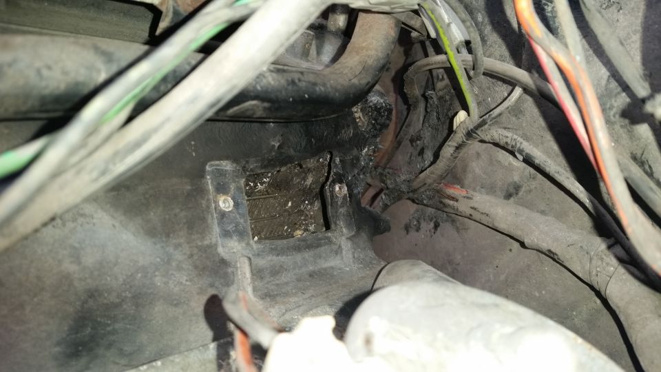 Close-up of vehicle wiring and a black plastic mounting bracket with screws