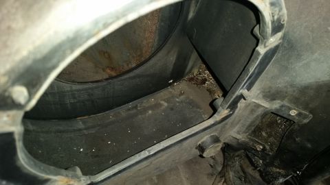 1985 Ford Bronco - This image shows the interior of a vehicle's wheel well, filled with dirt and debris.