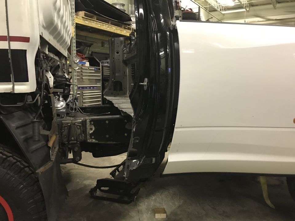 Damaged white truck cab and chassis, front section removed