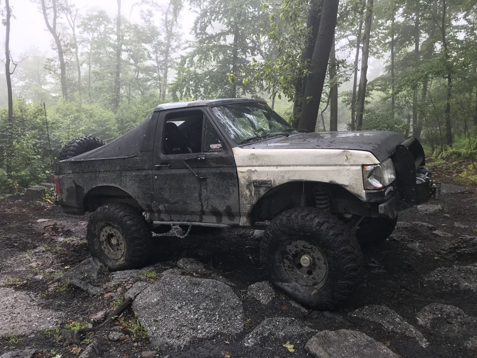 Muddy 1989 Ford Bronco with off-road tires on rocky terrain
