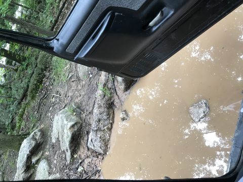 1989 Ford Bronco - The interior of a vehicle is shown from the driver's perspective, looking out at a muddy puddle.
