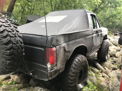 1989 Ford Bronco - Modified 1989 Ford Bronco navigating a rocky trail with a soft top cover.
