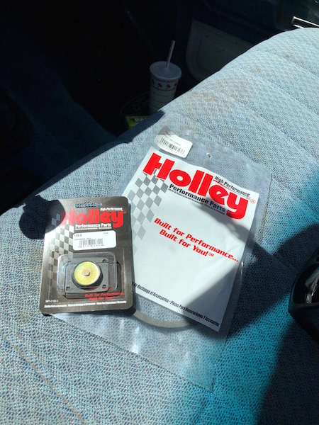 1981 Ford Bronco - Holley performance parts are laid out on a car seat, with a drink cup nearby.