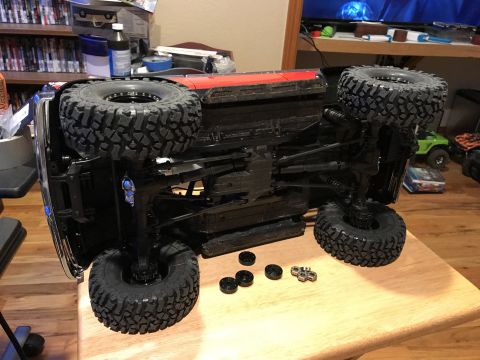 1989 Ford Bronco - This RC truck chassis is shown upside down, revealing its suspension and large off-road tires. Another RC vehicle is visible in the backgro…