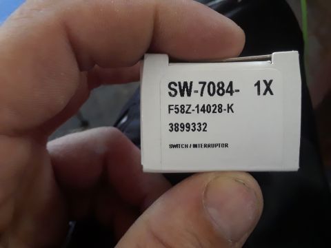 1999 Ford E250 - A hand holds a white box labeled with part number SW-7084-1X and "SWITCH / INTERRUPTOR".