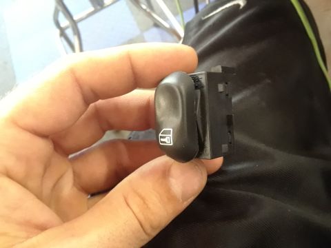 1999 Ford E250 - A close-up shows a power window switch with a window icon, held in a person's hand.
