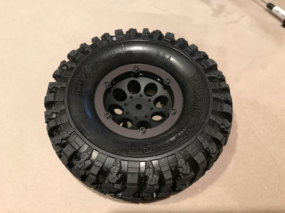 RC car tire with 'PIT BULL ROCK BEAST' text and a black wheel with brown trim