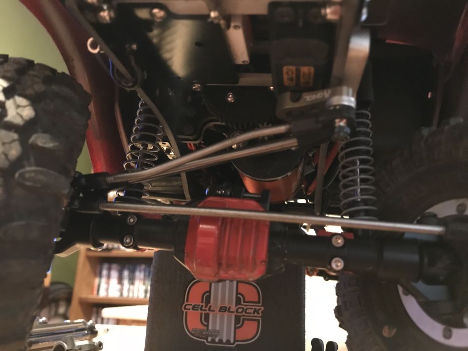 Undercarriage of a modified RC vehicle with suspension and red differential.