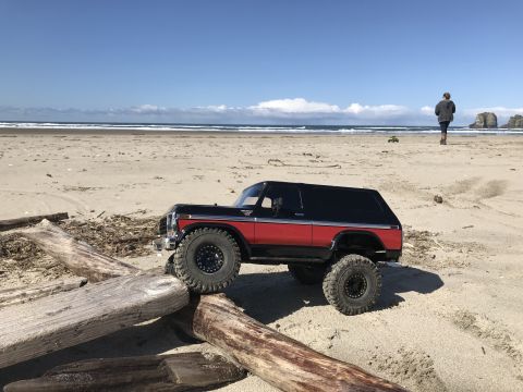 1989 Ford Bronco - Toy Bronco model on a beach under a clear blue sky.