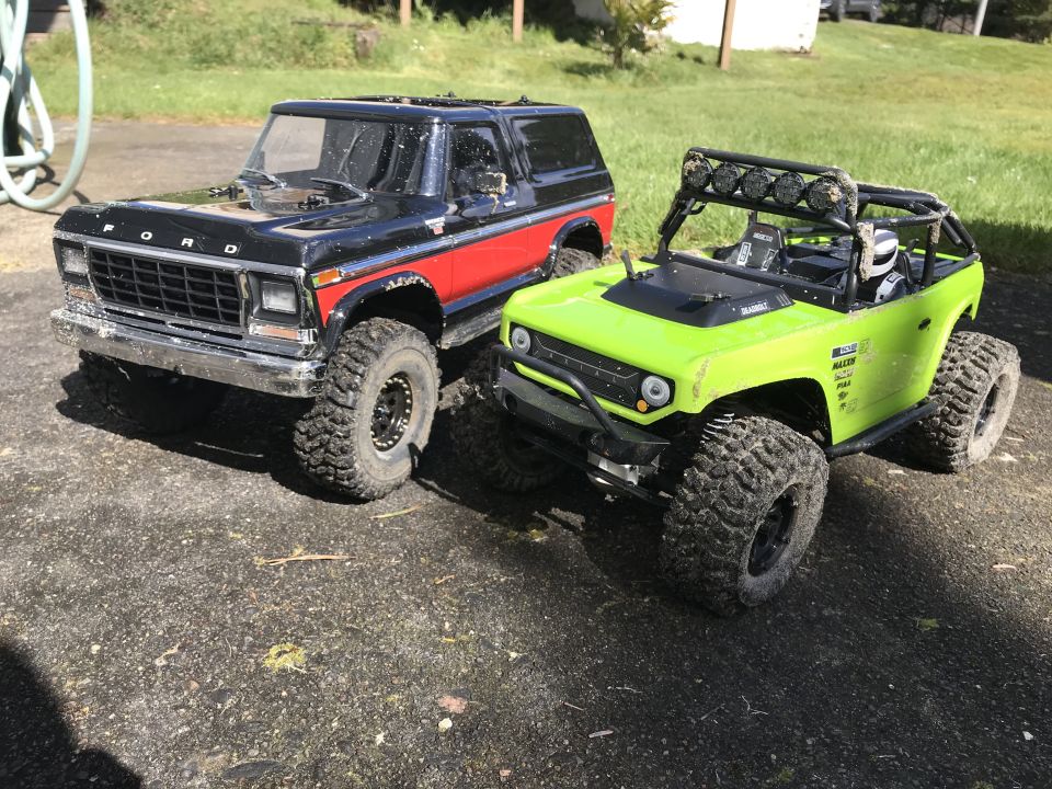 Black and red Ford Bronco and lime green rock crawler RC vehicles parked side-by-side.