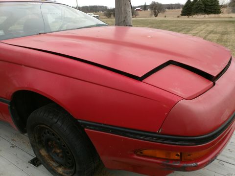 Red 1989 Ford Probe, right front quarter view, hood open, pop-up headlights closed.