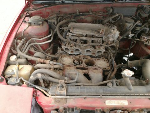 1989 Ford Probe — Disassembled V6 engine in a red vehicle, showing engine block and intake manifold.