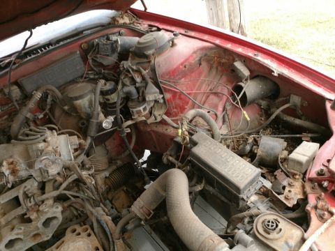 1989 Ford Probe — Close-up view of a red vehicle's engine bay with visible engine parts, hoses, and a fuse box.