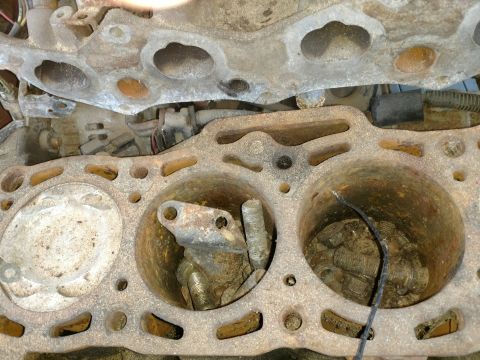 1989 Ford Probe — Close-up of a rusted engine block with two cylinders visible, containing debris and metal parts.