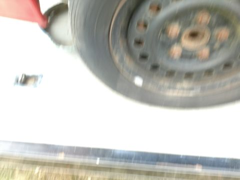 1989 Ford Probe — Blurry close-up of a car wheel, tire, and red fender.