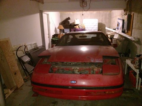 Red Ford Probe with hood open in a garage.