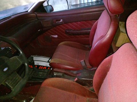 Interior of a 1989 Ford Probe showing red seats, steering wheel, and shifter.