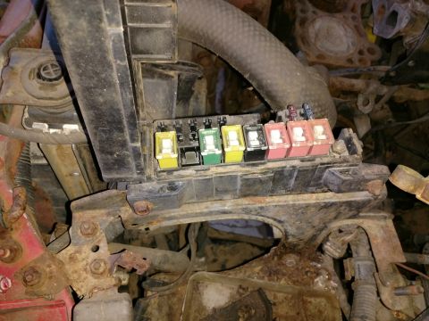 1989 Ford Probe — Close-up of a car fuse box with yellow, green, black, and pink fuses on a rusted bracket.