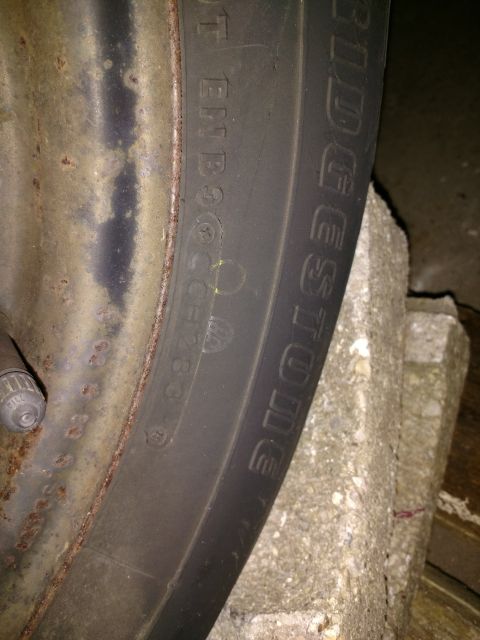 1989 Ford Probe — Close-up of a Bridgestone tire on a rusty wheel, resting on a concrete block.