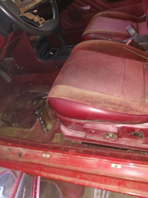 1989 Ford Probe — Interior of a red vehicle showing the driver's seat, dashboard, and floor with tools.