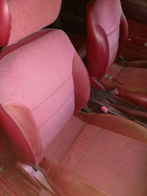 1989 Ford Probe — Red fabric and vinyl car seats, driver and passenger side, dusty and worn.