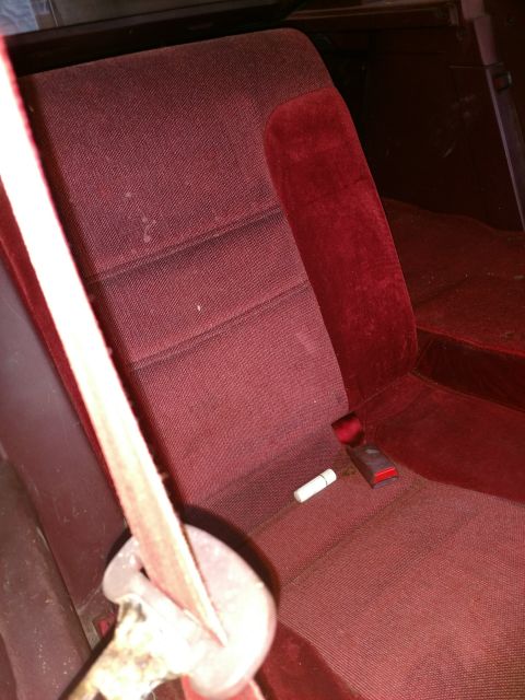 1989 Ford Probe — Red car interior with fabric seat, seatbelt, lipstick, and lighter.