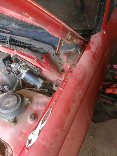 Red 1989 Ford Probe engine bay with wiper motor and pliers.