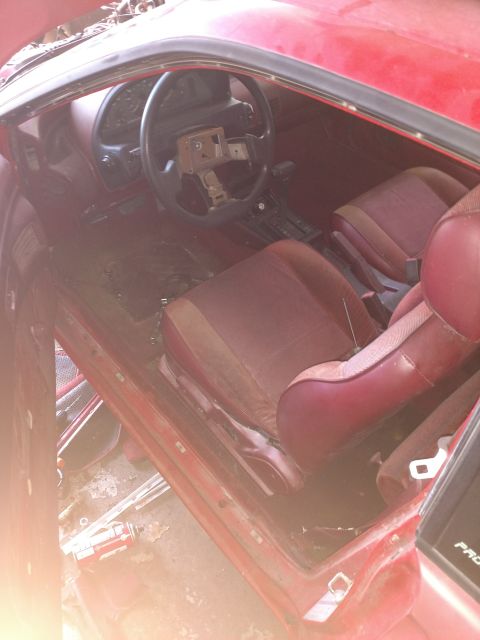 Interior of a red 1989 Ford Probe, showing dashboard, steering wheel, and seats.