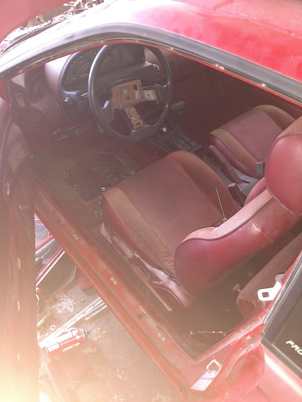 Interior of a red 1989 Ford Probe, showing dashboard, steering wheel, and seats.