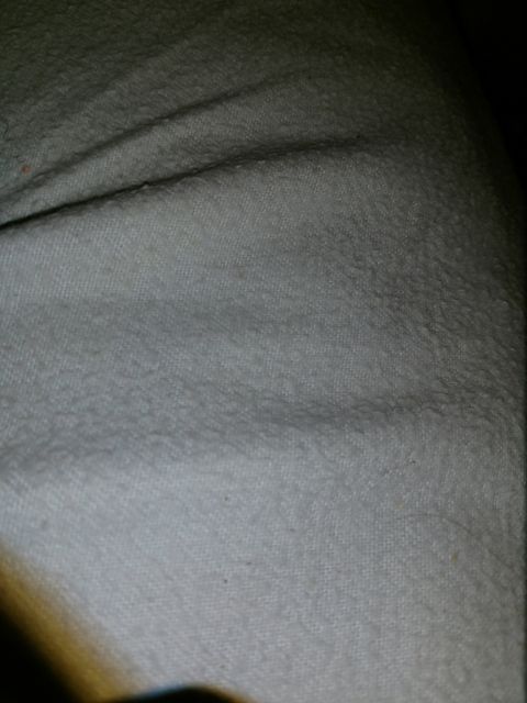 Close-up of light-colored textured fabric with folds and creases.