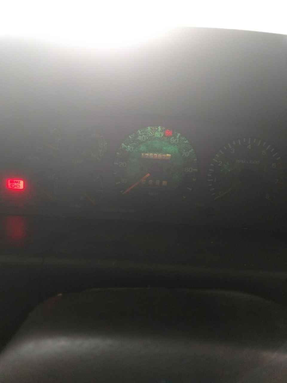Car dashboard with illuminated speedometer, odometer reading 175397, and red brake light.