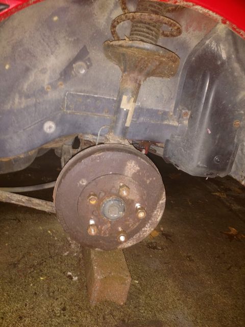 1989 Ford Probe - A close-up view of the rear drum brake assembly and suspension components of a vehicle, likely a 1989 Ford Probe, showing significant rust.…