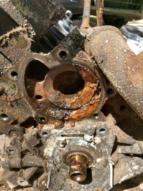 1989 Ford Probe - This is a close-up view of a heavily corroded and rusted engine component, likely a water pump housing, with significant debris and buildup.