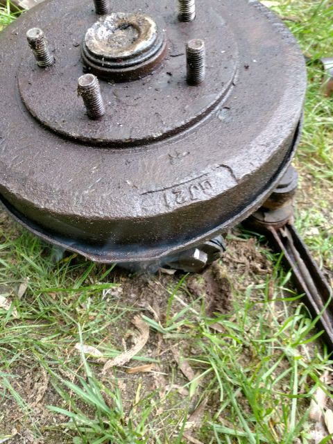 1989 Ford Probe - A close-up view of a rusty, dark-colored brake drum with visible lug studs and a stamped marking that appears to read "GJ21". The part is r…