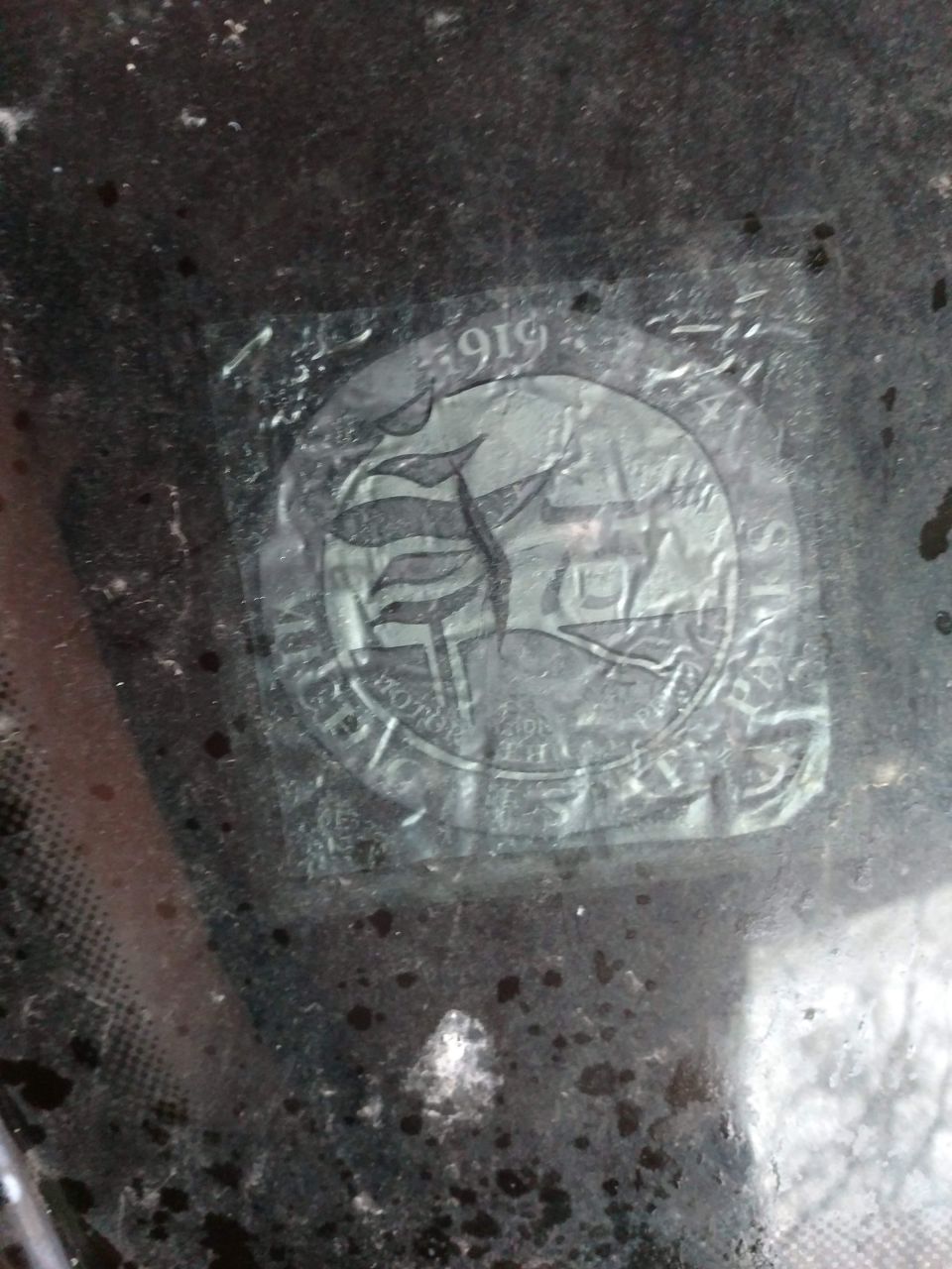 Close-up of a sticker on a windshield with "1919" and a circular emblem.