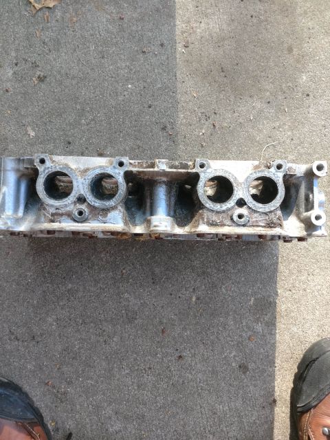 1989 Ford Probe - A disassembled aluminum engine cylinder head is shown lying on a concrete surface. The cylinder head has multiple circular openings for val…