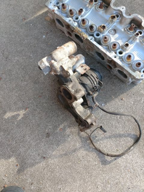 1989 Ford Probe - A disassembled engine cylinder head and turbocharger assembly are laid out on a concrete surface. The engine parts appear to be made of alu…