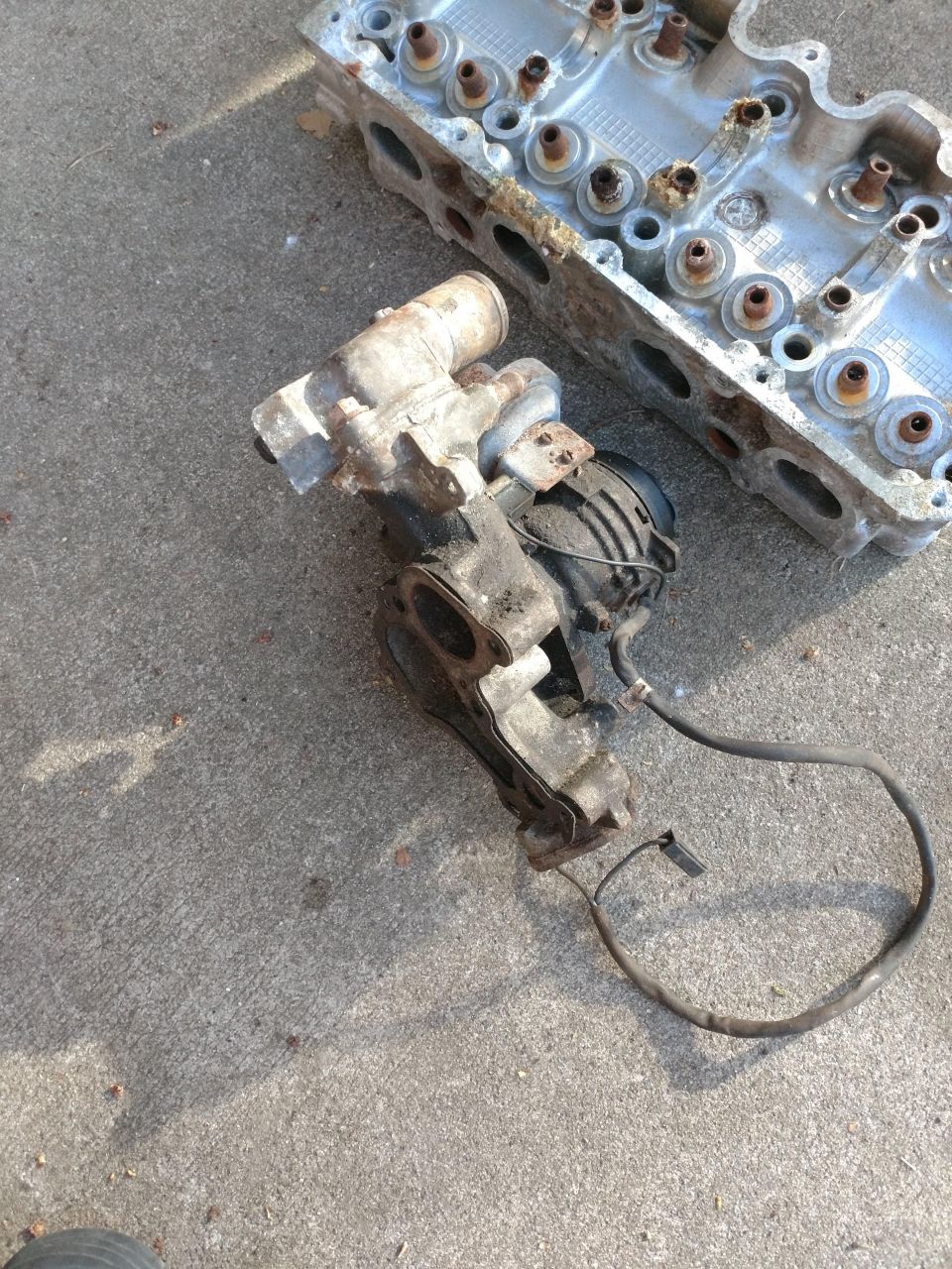 Disassembled engine cylinder head and turbocharger on concrete
