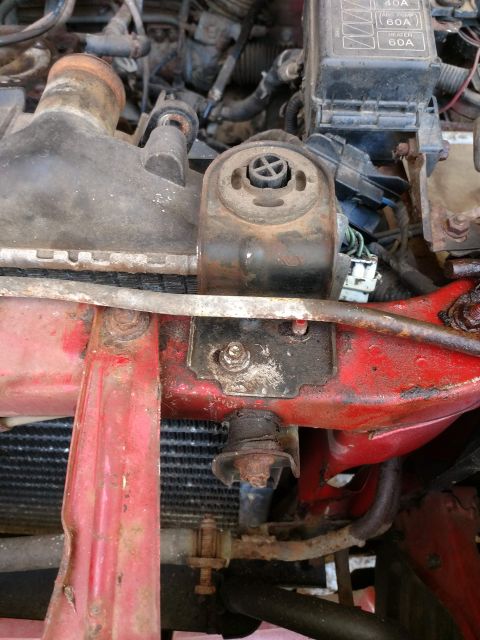 1989 Ford Probe - A close-up view of the engine bay of a 1989 Ford Probe, focusing on the radiator support structure and a fuse box. The engine components ar…
