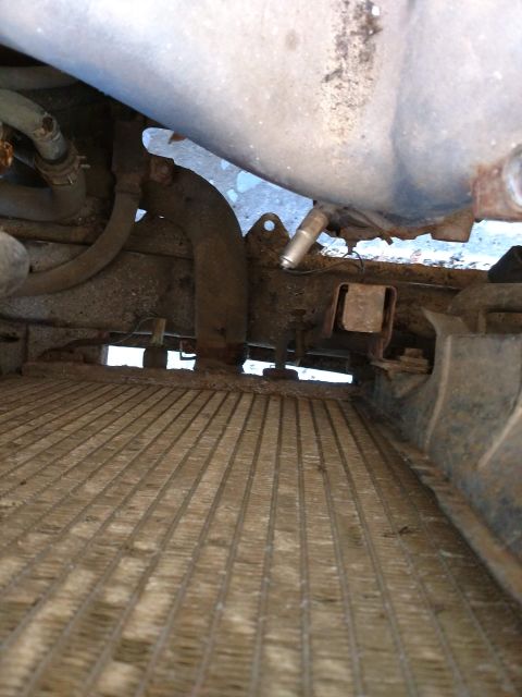 1989 Ford Probe - A low-angle view of the front of a vehicle's radiator and associated hoses and metal components. The radiator fins are visible and appear d…