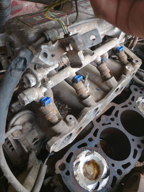 1989 Ford Probe - A close-up view of a dirty engine with fuel injectors visible. The engine block and cylinder head are partially disassembled.
