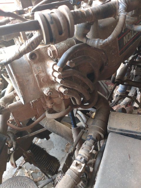 1989 Ford Probe - A close-up view of a dirty engine bay, focusing on hoses and electrical components. The image shows a section of the engine with various tu…