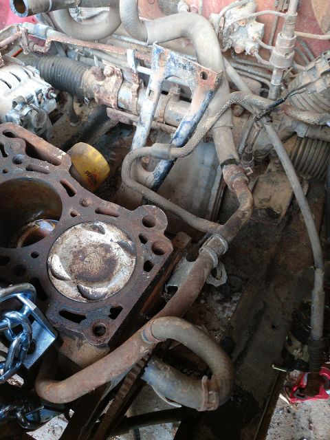 1989 Ford Probe - A close-up view of a rusty engine block with a piston visible, surrounded by hoses and other engine components. A yellow oil filter with "P…