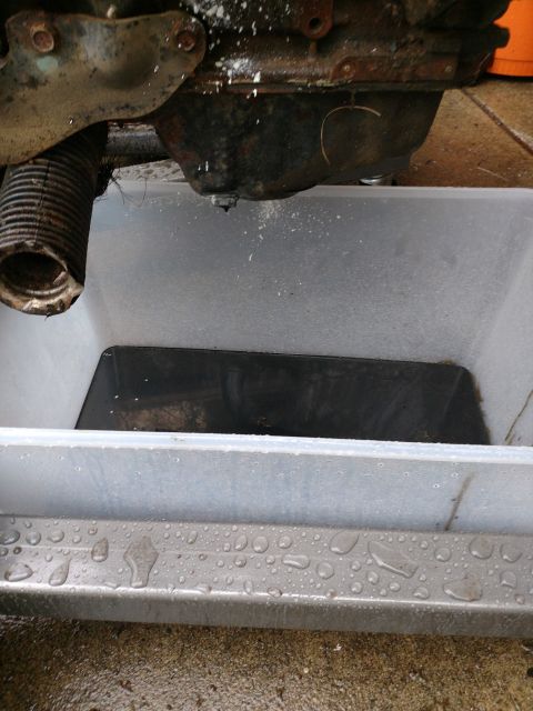 1989 Ford Probe - A close-up view of an engine's oil pan and a drain pan collecting dripping fluid. The engine appears to be part of a vehicle restoration or…