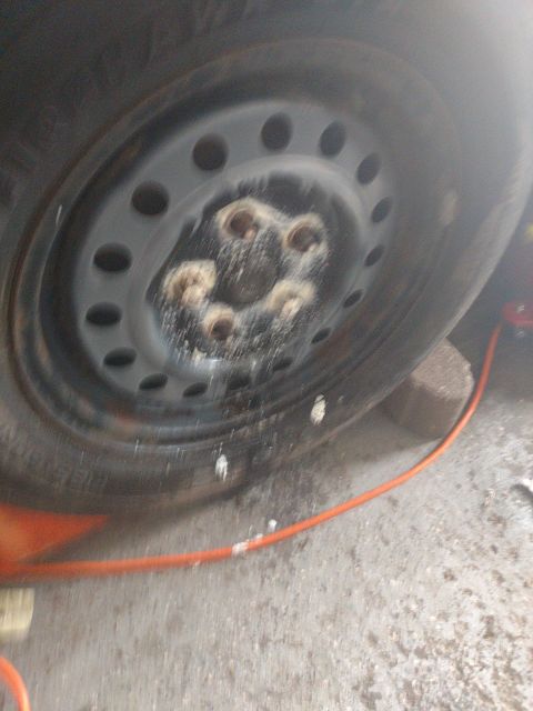 1989 Ford Probe - A close-up view of a car's wheel hub and lug nuts, which appear to be covered in a white, powdery substance. An orange hose is visible in t…